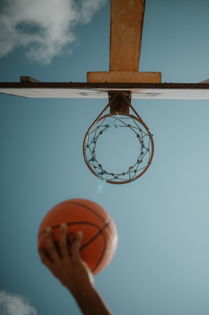 Photo by Marie-Kristin Krause A person holding a basketball up to a hoop